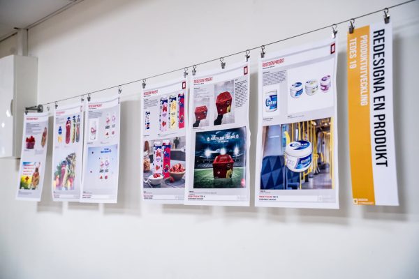 Ritningar på förpackningsdesign sitter uppsatta på en vägg.