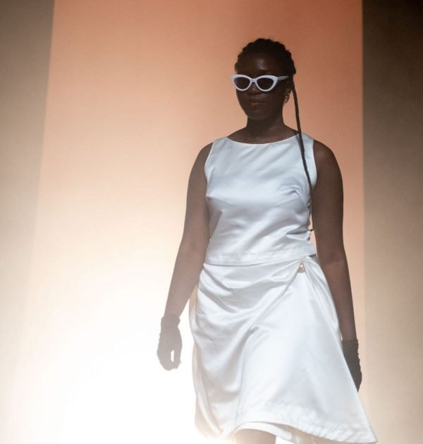 Elev med designade kläder på catwalk.