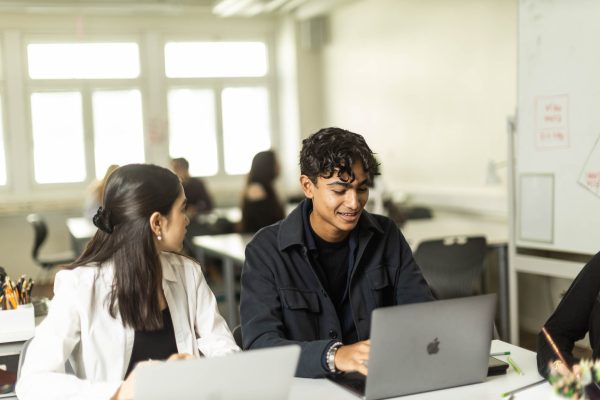 Två elever sitter med varsin dator i ett klassrum.