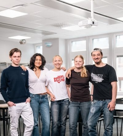 Flera elever står och ler i klassrummet
