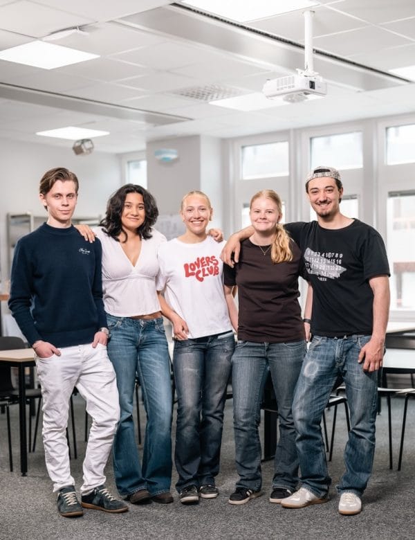 Flera elever står och ler i klassrummet