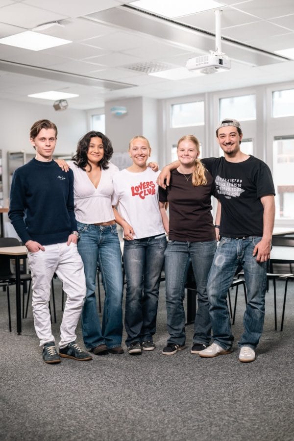 Flera elever poserar och ser glada ut i klassrummet