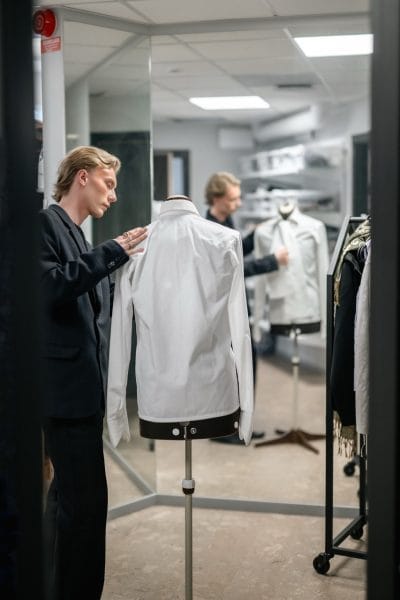 En elev står och klär en provdocka med en design