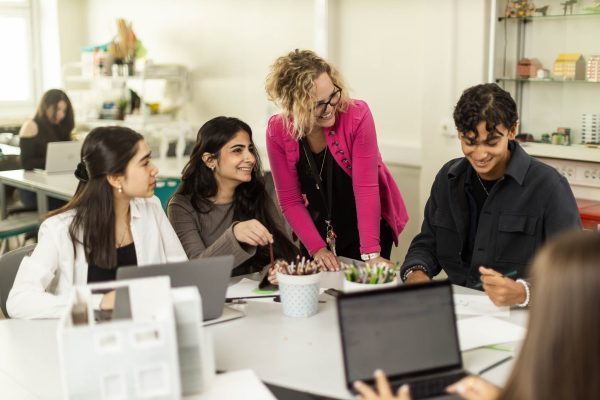 Elever arbetar kreativt med en lärare vid bordet