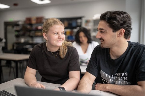 Två elever ler mot varandra i klassrummet